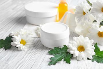 Obraz na płótnie Canvas Jar with cream and chamomile flowers on wooden table
