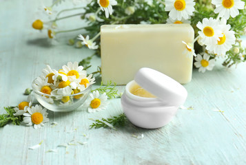 Composition with skin care products and chamomile flowers on wooden table