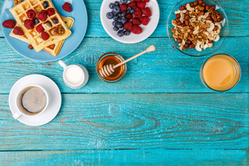 Homemade waffles, fresh raspberries and blueberry, cup of coffee, milk, nuts and honey.