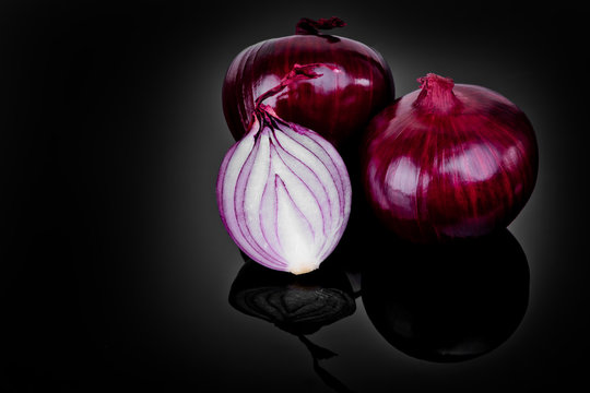 Red onion and half slice on black background with reflect.