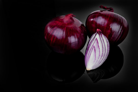 Red onion and half slice on black background with reflect.