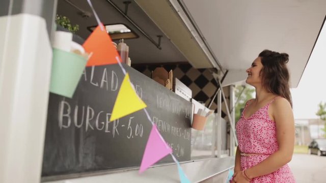 happy young woman ordering wok at food truck