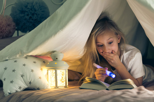 Girl with flashlight reading book