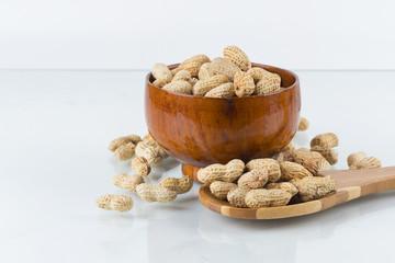 Peanuts in wooden bowl on isolated white background