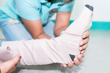 Nursing student train to first aid patient's leg sprain with elastic bandage.