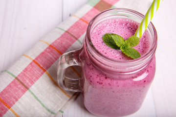 Berry milkshake or smoothie with ingredients and mint. Healthy drink in mason jar.