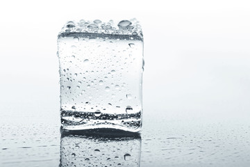 Transparent ice cube with reflection on white