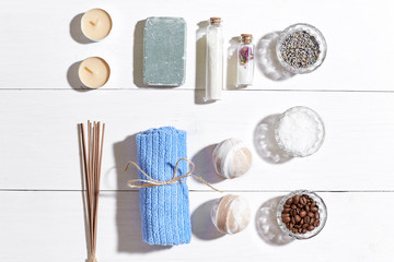 Spa products. Bath salts, dry flowers lavender, soap, candles and towel. Flat lay on white wooden background, top view.