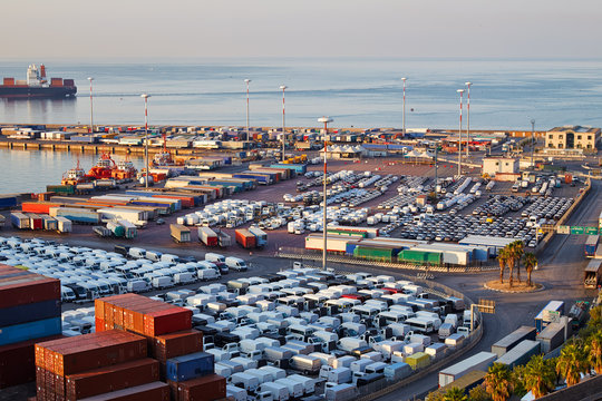 Port terminal with containers, new cars and wagons in the early morning