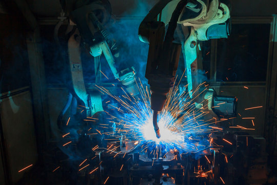 Robots are welding metal part in car factory