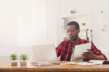 Serious young black happy businessman in office, work with laptop