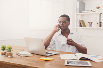 Obraz na płótnie Canvas Young black businessman call mobile phone in modern white office