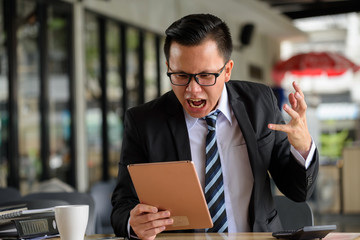 Angry Businessman see bad news by tablet