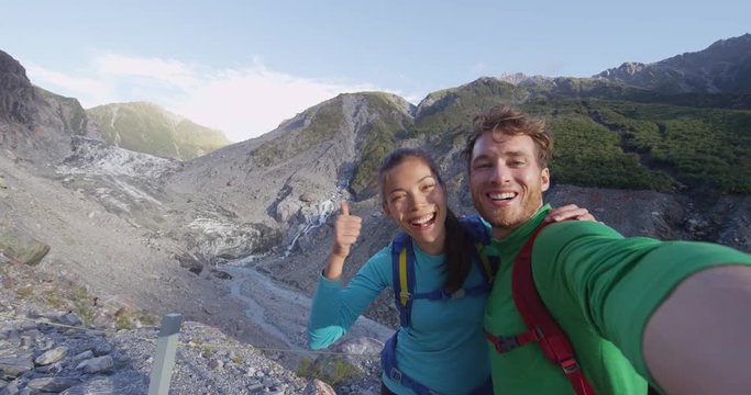 Couple selfie video. New Zealand tourists smiling happy in nature by Franz Josef Glacier, Westland Tai Poutini National Park, South Island, New Zealand. Couple having fun on travel. SLOW MOTION.