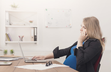 Pregnant business lady at work talking on phone