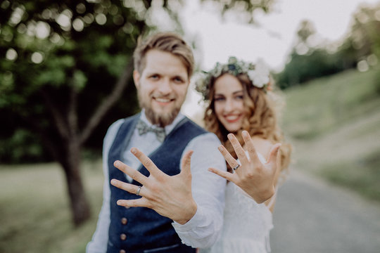 Bride and groom with wedding rings in nature.