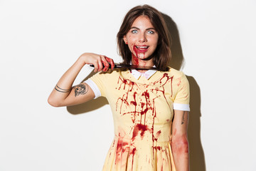 Mad smiling zombie woman cutting her throat with a knife