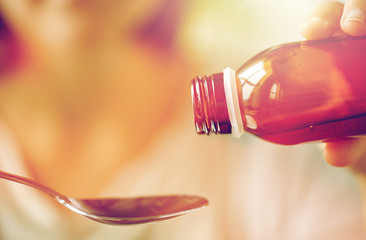 woman pouring medication from bottle to spoon