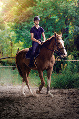 Young pretty girl riding a horse with backlit leaves behind