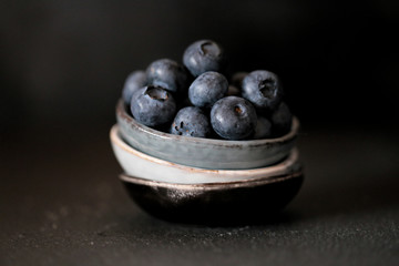 blueberry berries in a dark key. blueberries in three small ceramic cups on a dark background. blueberry harvest season
