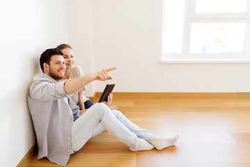 happy couple with tablet pc computer at new home