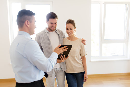 Couple And Realtor With Tablet Pc At New Home