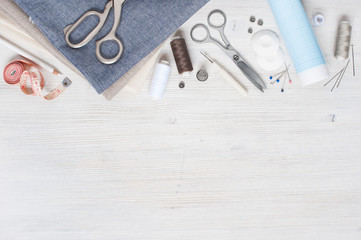 Various fabric and sewing tools on the white wooden table - obrazy, fototapety, plakaty