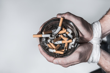 Heavy smoker holding ash-pot with tied arms