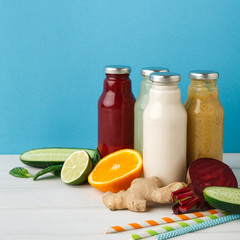 Assortment of detox smoothies in glass bottles on wall background.