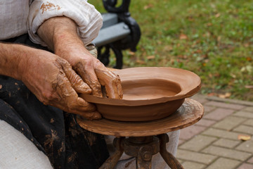 Hands of a potter, creating an earthen plate on the circle