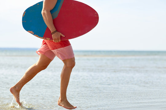 young man with skimboard on summer beach