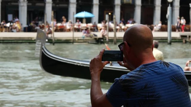 Man filming with his Samsung S6 a gondola in Venice Italy