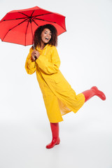 Full length image of joyful african woman in raincoat