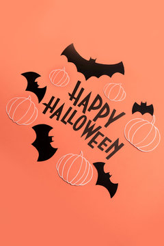 Hand written phrase Happy Halloween with pumpkins and bats near it