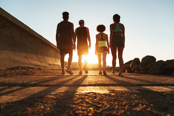 Full length back view image of four fitness people walking