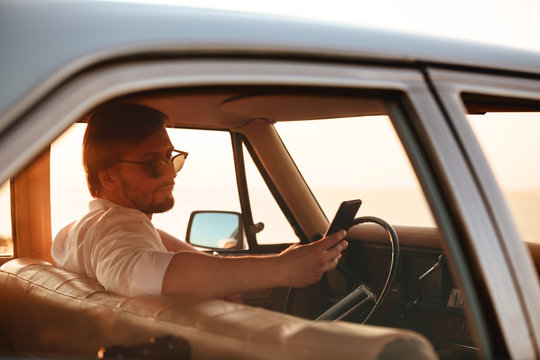 Side view of Handsome Man sitting in retro car