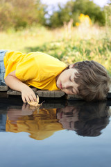 boy play with autumn leaf ship in water, chidren in park play with leaf in river