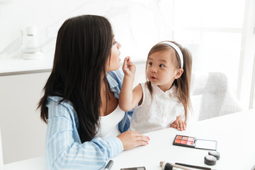 Cute little asian girl doing make up for her mother