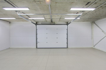 empty parking garage, warehouse interior with large white gates and gray tile floor