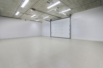 empty parking garage, warehouse interior with large white gates and gray tile floor