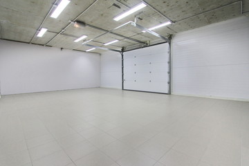 Fototapeta premium empty parking garage, warehouse interior with large white gates and gray tile floor