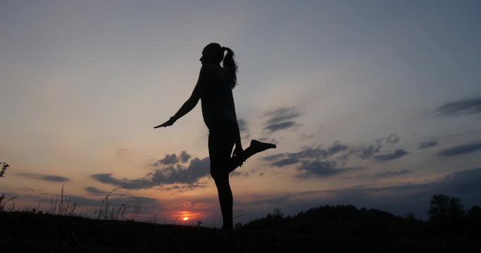 Silhouette young woman practicing yoga at sunset 4k