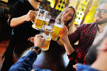 Friends clink glasses of beer glasses close-up on the background of the pub