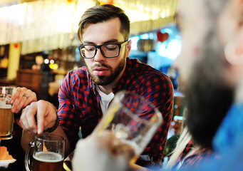 A company of friends drink beer and clink glasses at a pub