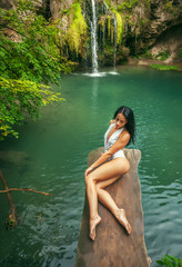Fototapeta premium Beautiful woman relaxing near tropical waterfall