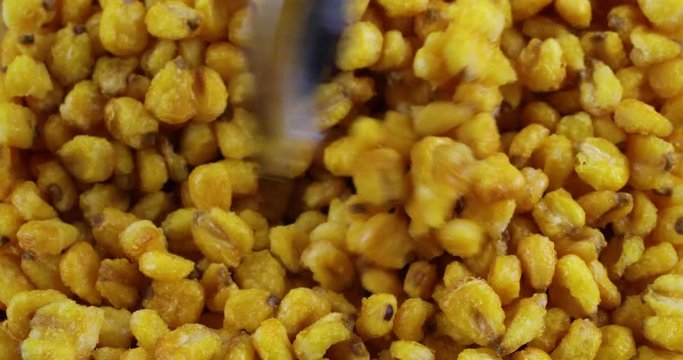 Close video of stirring toasted corn nuts with a spoon.