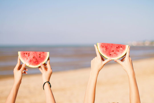 Two young female friends  on the sea shore enjoying  with watermelon.