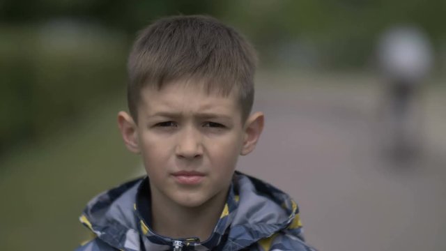 portrait of a serious boy with a tence glance looking at the camera, close-up heavy face