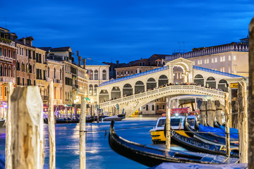 Fototapeta na wymiar Venice, Italy. Rialto bridge and Grand Canal at twilight blue hour. Gondolas on the foreground. Tourism and travel concept.
