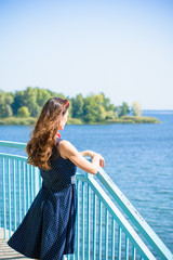 Fototapeta premium Portrait nice middle age thin woman in american pin up style. Lady in deep blue polka dot dress, red sunglasses and scarf